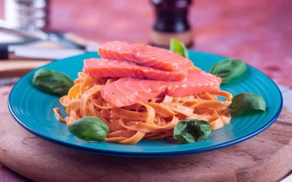 Tagliatelle al Salmone served with salmon fillets, creamy sauce, and fresh herbs.